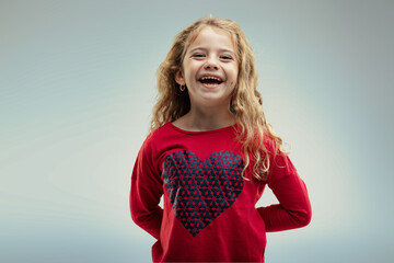 Joyful girl laughs in heart-patterned sweater