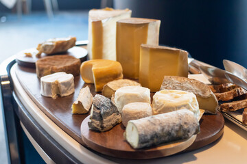 A variety of delicious cheeses are arranged on a wooden board.