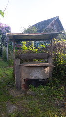 A well is sitting in a yard with a wooden bench