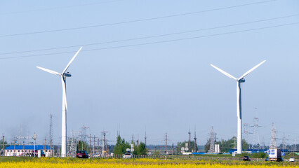 Two wind turbines are in the distance, with a clear blue sky above them