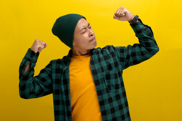Confident Asian man, dressed in a beanie hat and casual shirt, is making a strong gesture by...
