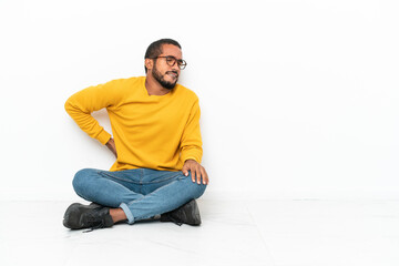 Young Ecuadorian man sitting on the floor isolated on white wall suffering from backache for having...
