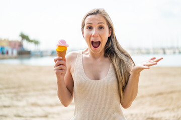 Young blonde woman with a cornet ice cream at outdoors with shocked facial expression