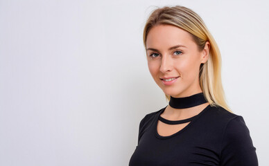 Obraz premium Attractive young blonde woman wearing black top, smiling. Plain white background with copy space on left.