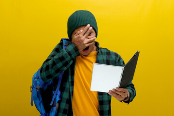 Funny Asian student, wearing a beanie hat and casual clothes, carrying a backpack, appears shocked...
