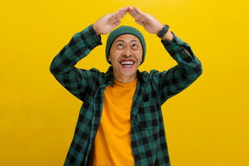Happy Young Asian man with a beanie hat and casual clothes is making a hand gesture above his head,...