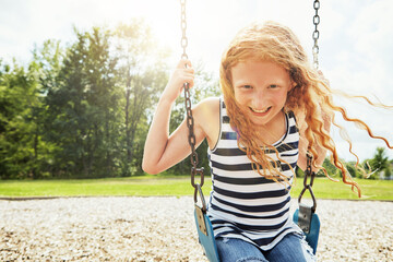Girl, portrait and smile with nature, swing and park for outdoor fun or play with fresh air. Child, playground and development with summer, freedom and school holiday or break outside for happiness