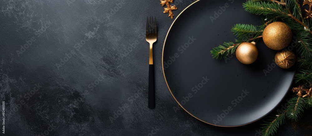 Poster Top view of a Christmas table setting on a black stone background The elegant arrangement includes an empty black ceramic plate a fir tree branch and gold accessories The image has copy space availab