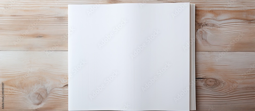 Poster A blank book cover template with an open page on the front side positioned on a white wood background in a flat lay copy space image
