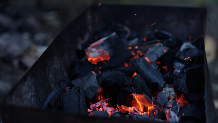 Handheld shot of charcoal in brazier, preparation for bbq