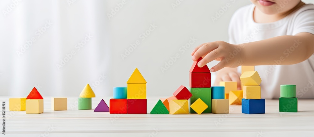 Poster child playing with colorful wooden bricks on a white wooden table in a learning and education concep