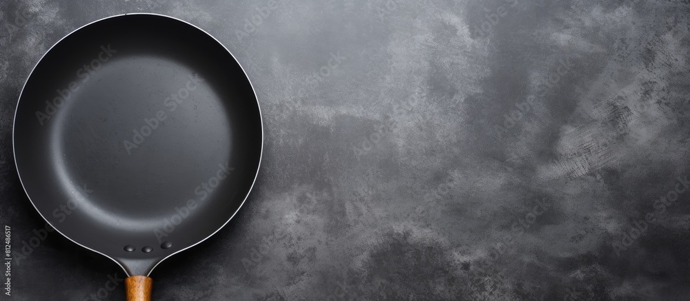 Aufkleber A centered top view of a black frying pan on a gray black background creating a solid color composition with ample copy space image