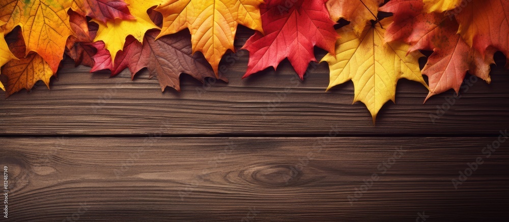 Poster a close up image of colorful autumn leaves in red and yellow hues placed on a brown wooden backgroun