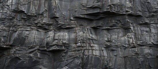 A close up of a rough and dilapidated stone wall resembling a dark cliff The gray texture of the stone or rock mountains creates a background with plenty of copy space for geology and mountaineering