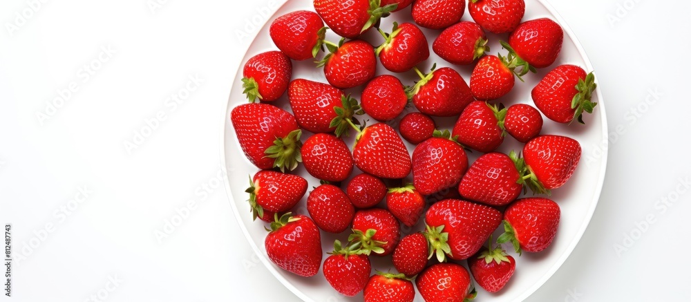 Poster A close up view from above of a plate containing fresh and healthy strawberries The plate is isolated on a white background offering copy space for text