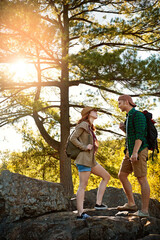 Nature, hiking and couple walking with conversation, trees and adventure holiday in mountain. Trekking, man and woman on sustainable travel vacation together in park with chat, rocks and outdoor date