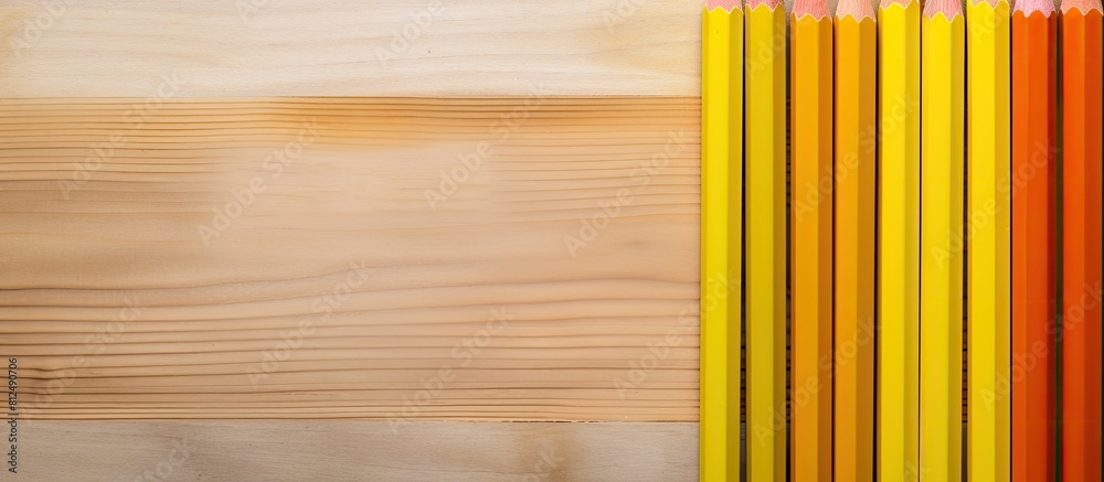 Poster A top down view of colorful pencils and a yellow sheet of paper creating a flat lay composition with space for additional content in the image