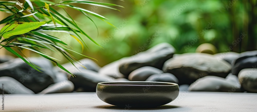 Aufkleber bowl filled with stones surrounded by bamboo grove on mat background copy space image
