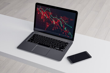 Close up of white office desk with smartphone and downward red forex chart on laptop screen. Blurry background. Stock, trade and report concept. 3D Rendering.