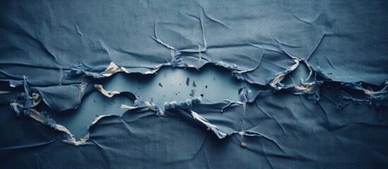 A copy space image of ripped and destroyed denim fabric featuring a texture of torn blue jeans