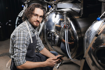 Technology tablet inspection and quality control manufacturing and alcohol fermentation beer in tank. Brewer man in brewery drink factory for production, digital business owner