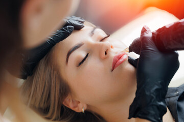 Permanent makeup artist at work tattoo for red lips for woman in beauty salon