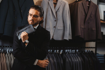 Portrait business gentleman in glasses and suit buy skin bag in shop store classic clothes