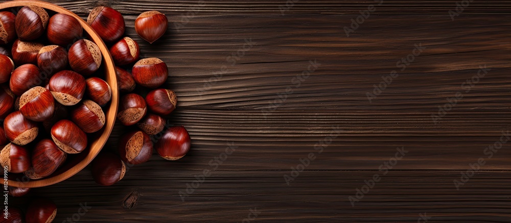 Poster top view of a wooden table with a bowl of roasted sweet chestnuts there is ample space available for