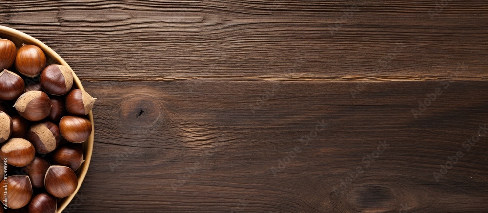 Poster top view of a wooden table with a bowl of roasted sweet chestnuts there is ample space available for
