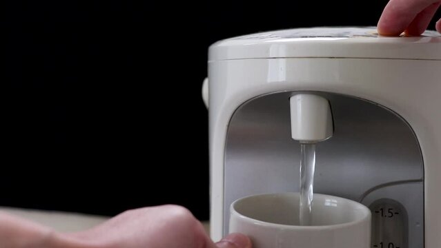 電気ポットからマグカップにお湯を注ぐ