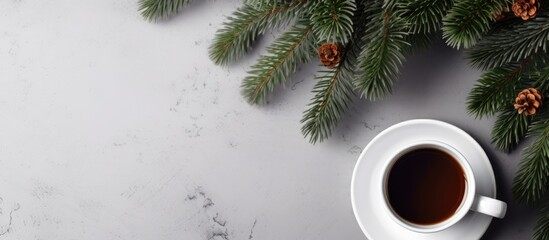 A white coffee cup placed on a gray surface accompanied by a Christmas fir tree branch The picture follows a flat lay style and provides ample copy space