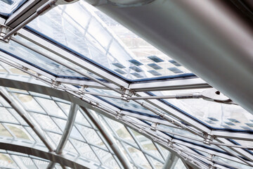Glass roof with small solar panels in modern round building. Metal steel mount of glass cupola,...