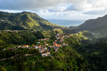 Fototapeta premium Madeira Island landscape, small village on hills and green lush forest. Aerial drone view. Portugal travel.