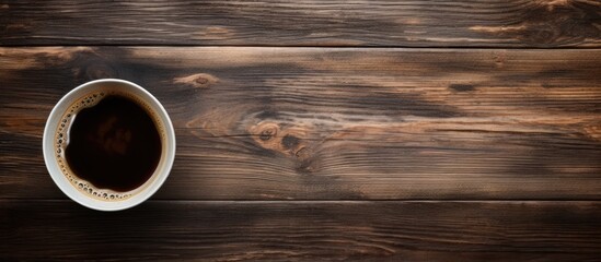 A top down perspective showing an old wooden surface with a cup of black coffee perfect for a copy space image 108 characters - Powered by Adobe