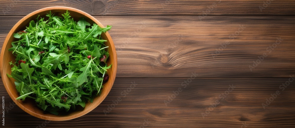 Poster a top down view of a wooden background featuring a bowl of fresh rucola salad with available copy sp