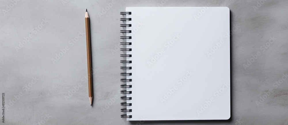 Fototapete Top down view of a gray background showcasing a blank spiral notebook and a pencil accompanied by generous empty space for text input. Creative banner. Copyspace image