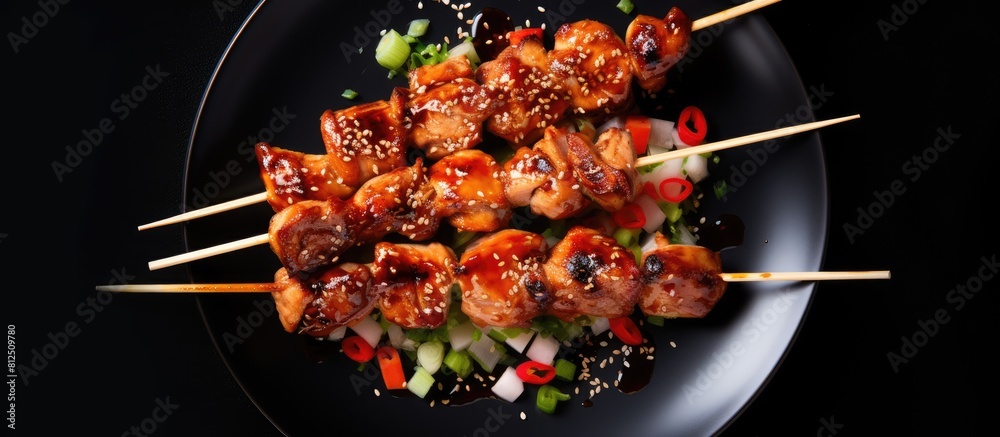 Poster top down view of teriyaki chicken skewers on a plate set against a black background ample space avai