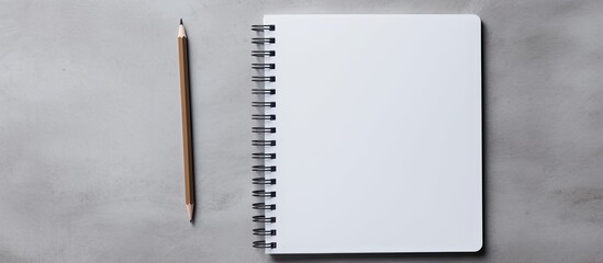 Top down view of a gray background showcasing a blank spiral notebook and a pencil accompanied by generous empty space for text input. Creative banner. Copyspace image