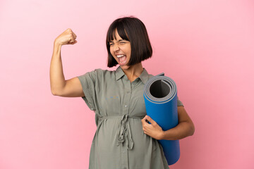 Fototapeta premium Woman over isolated background pregnant and doing strong gesture while going to yoga classes