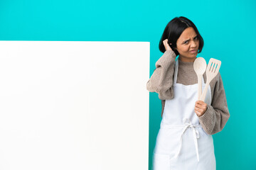 Young mixed race cook woman with a big placard isolated on blue background having doubts