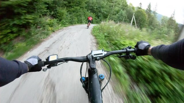 Point of view. Couple of cyclist riding electric mountain bikes in the forest. Concept of adventure, leisure time outdoors.