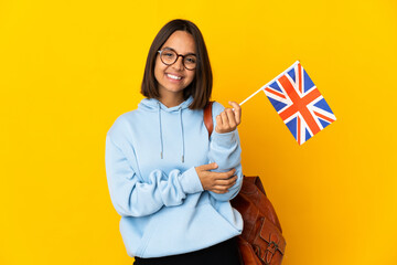 Young latin woman holding an United Kingdom flag isolated on yellow background laughing