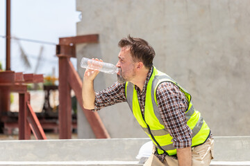 Worker man in hardhat drinking water at container cargo, Engineer man drinking water at the precast...