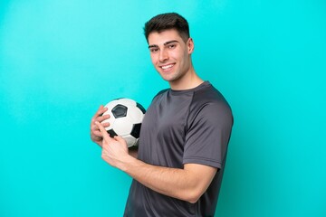 Young caucasian football player man isolated on blue background pointing back