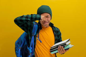 A funny young Asian student, dressed in a beanie hat and casual shirt and carrying a backpack,...