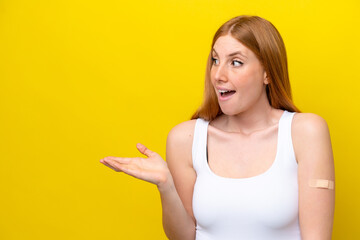 Young redhead woman wearing a band-aids isolated on yellow background with surprise facial expression