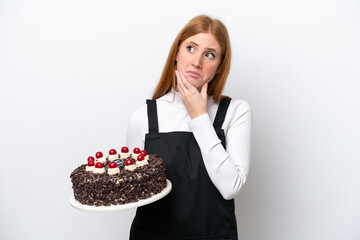 Young redhead woman holding birthday cake isolated on white background having doubts