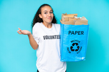 Young woman holding a recycling bag full of paper to recycle isolated on blue background making...