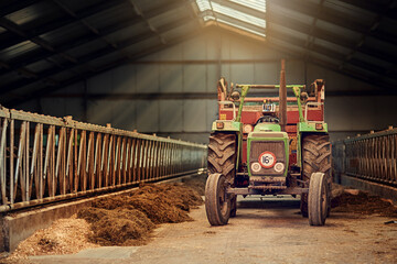 Obraz premium Farm, tractor and old machine in barn with dirt, rust and dust in storage warehouse on land. Vintage, retro and plow truck in abandoned factory shed or tools for farming production or agriculture