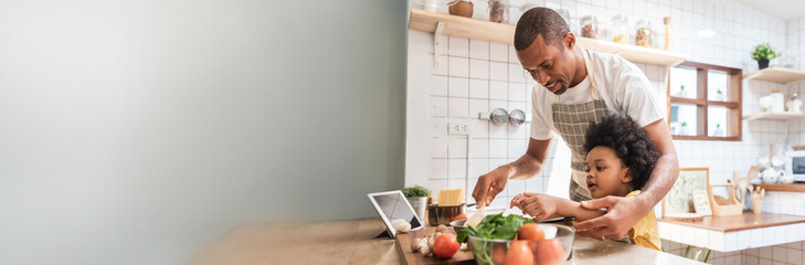 African American Little Afro child boy and his father cooking together in the kitchen at home